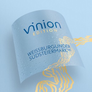 Gebogenes Vinion Edition Weissburgunder Südsteiermark DAC Etikett in Hellblau mit goldener Illustration und Wassertropfen.