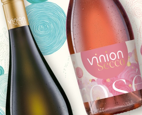 Zwei Vinion Secco Flaschen in White und Rosé mit farbigen Etiketten auf grafischem Musterhintergrund.